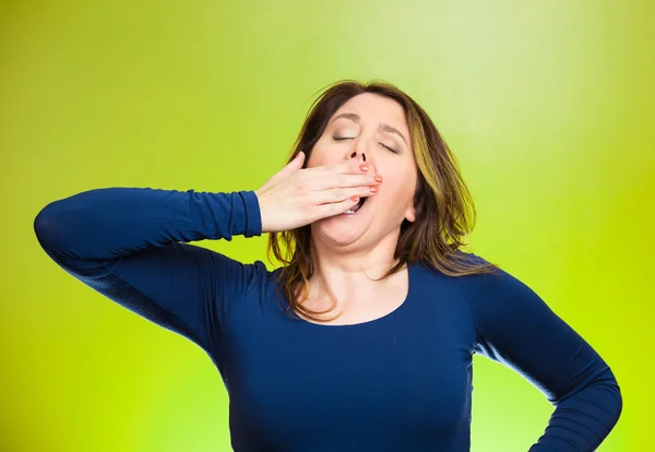 Sleep deprived young woman placing hand on mouth yawning — Stock Photo, Image