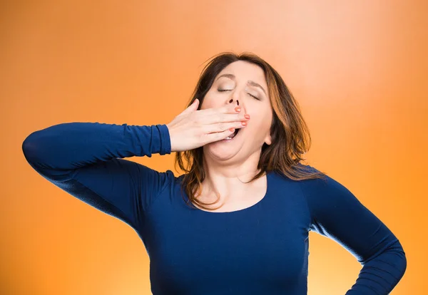 Sleep deprived young woman placing hand on mouth yawning — Stock Photo, Image