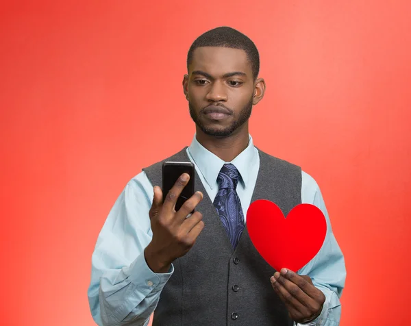 Man reading news, on smart phone, holding red heart — Stock Photo, Image