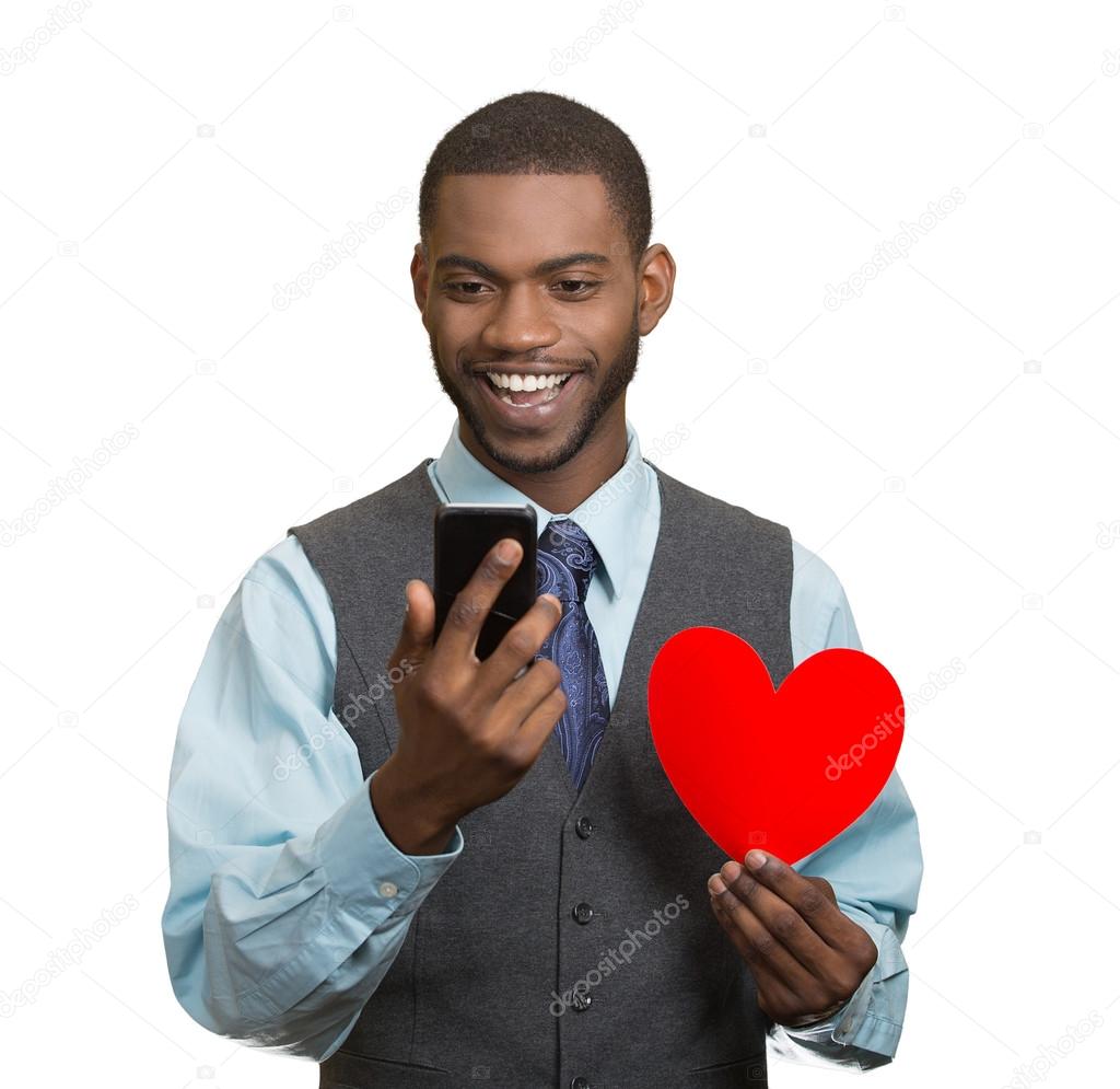 Man looking at his smart phone, holding red heart in hand