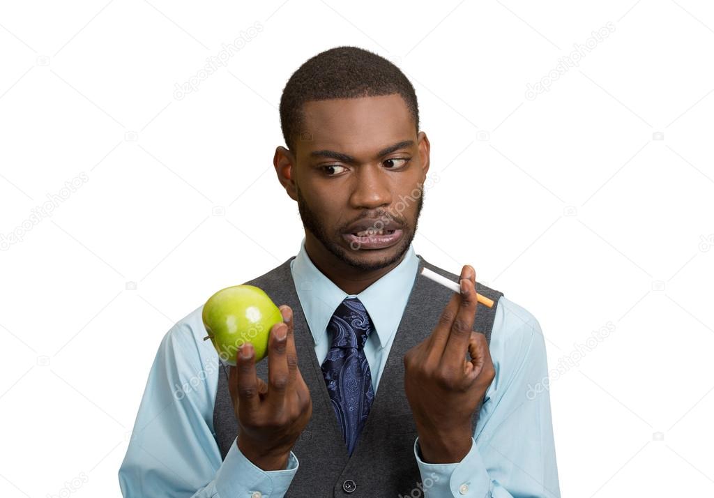 Man deciding on healthy life choices, craving cigarette versus green apple