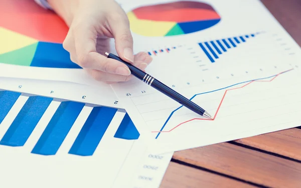 Manos femeninas apuntando con bolígrafo al gráfico del informe financiero empresarial — Foto de Stock