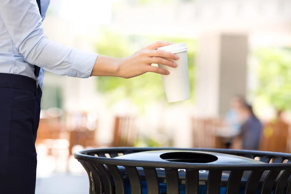 Frauenhand wirft leere Kaffeetasse in Papierkorb — Stockfoto