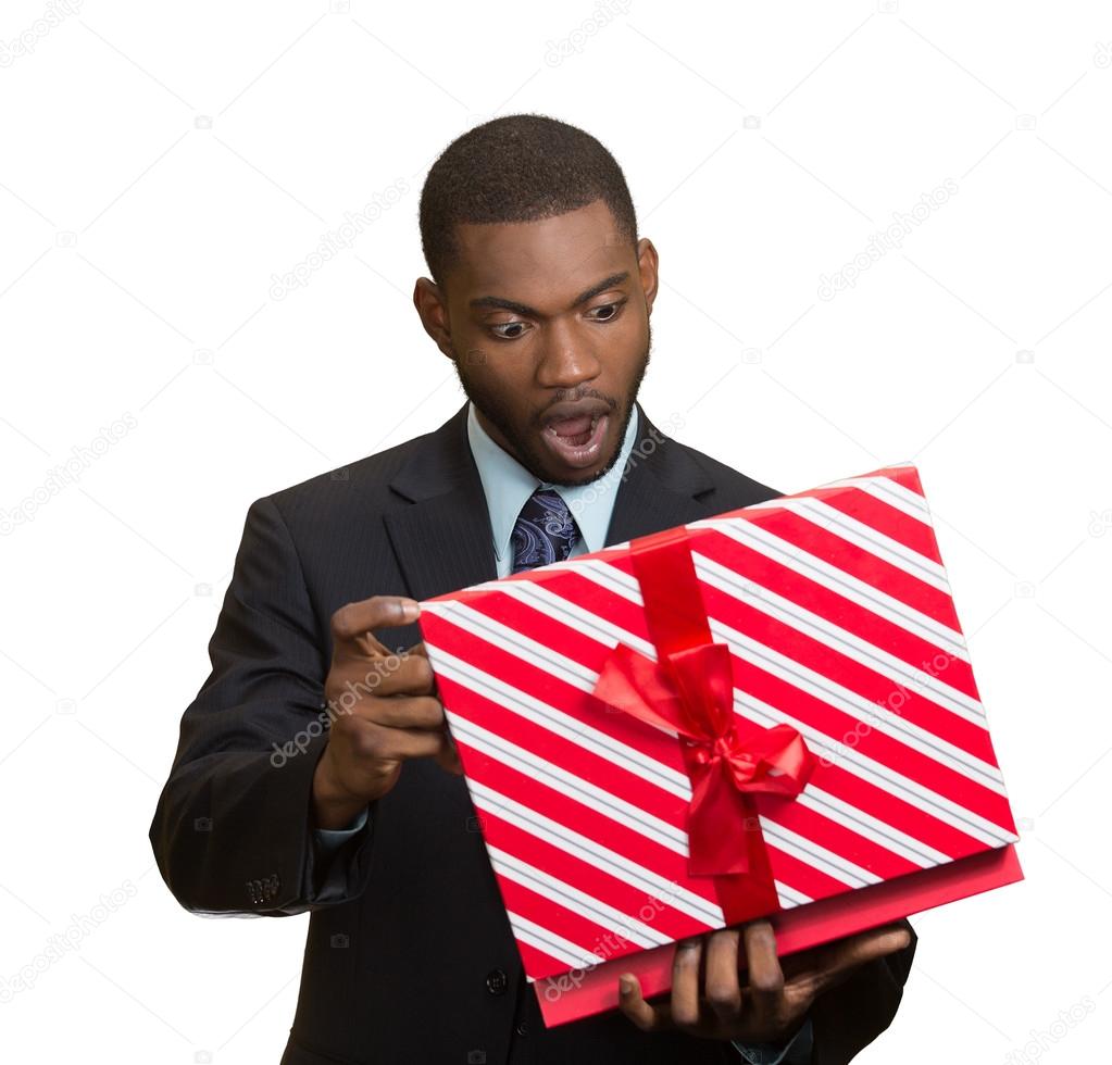 Surprised businessman about to open unwrap red gift box