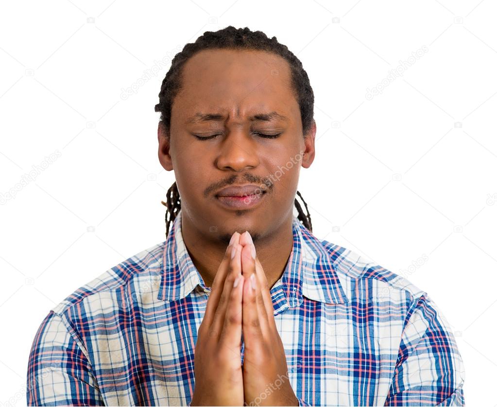 Young man praying hands clasped, hoping