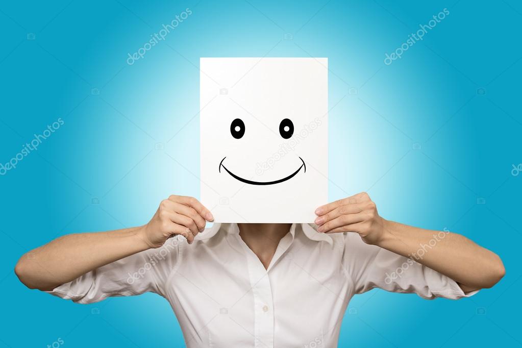 Woman covering face with smiling paper mask