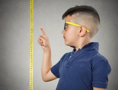 Child pointing at his height on measuring tape clipart