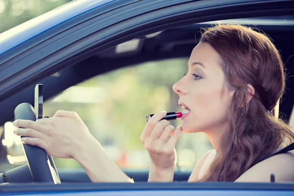 Jonge vrouw toepassing van make-up tijdens het rijden auto — Stockfoto