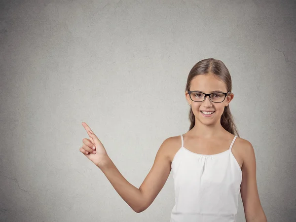 Adolescente chica con gafas apuntando a espacio de copia en blanco — Foto de Stock