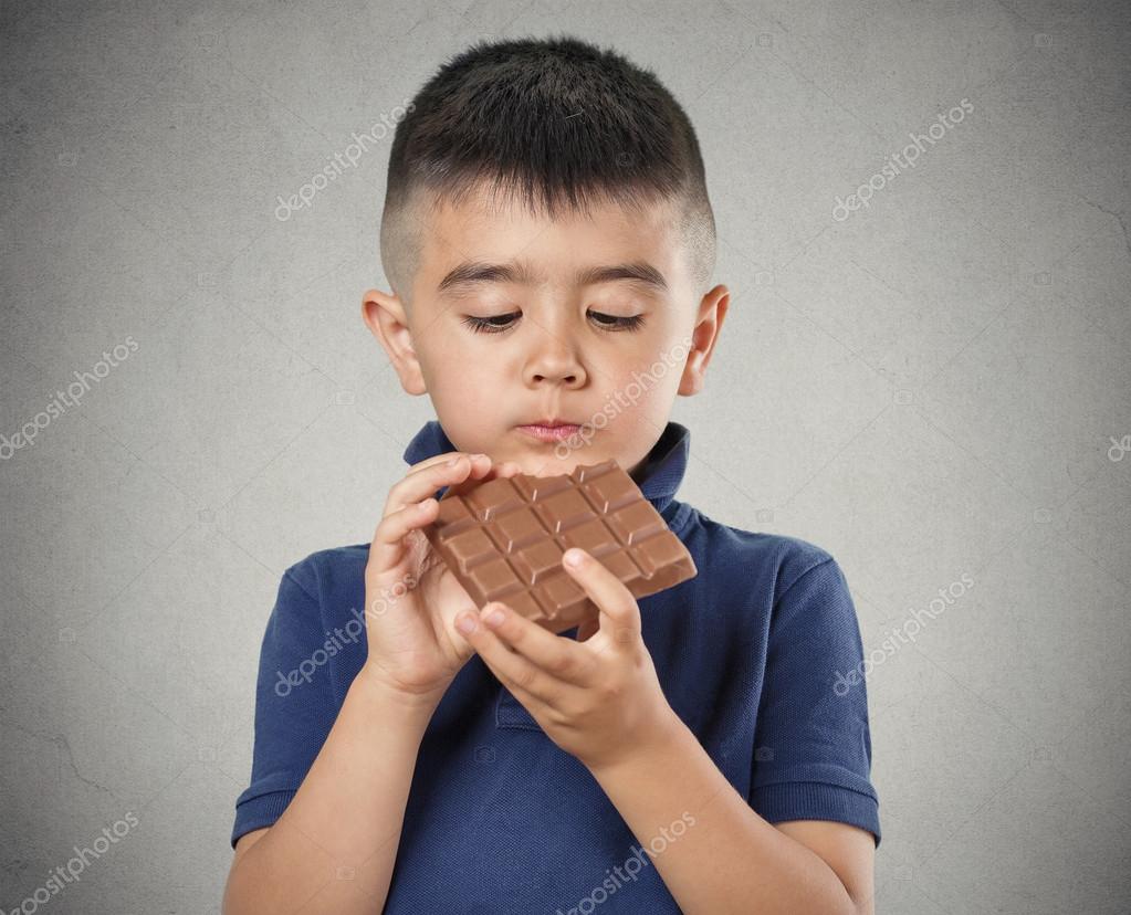 Niño comiendo barra entera de chocolate fotografía de stock