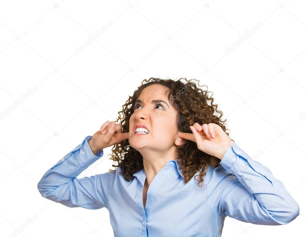 Stressed woman covering her ears, looking up