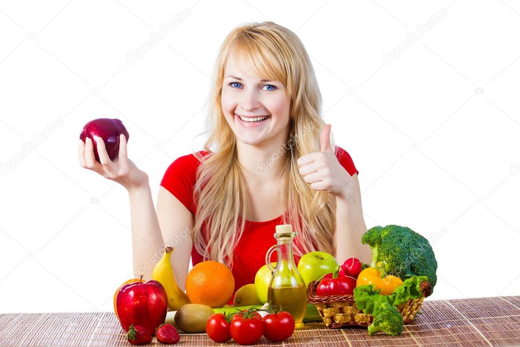Woman sitting at table with fruits and vegetables