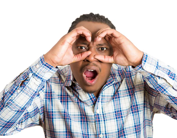 Hombre, mirando curioso, sorprendido, conmocionado a través de los dedos como binoculares —  Fotos de Stock