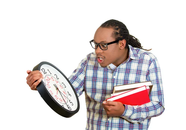 Man, with glasses, holding books, wall clock, anxious in anticipation of finals test — Stock Photo, Image