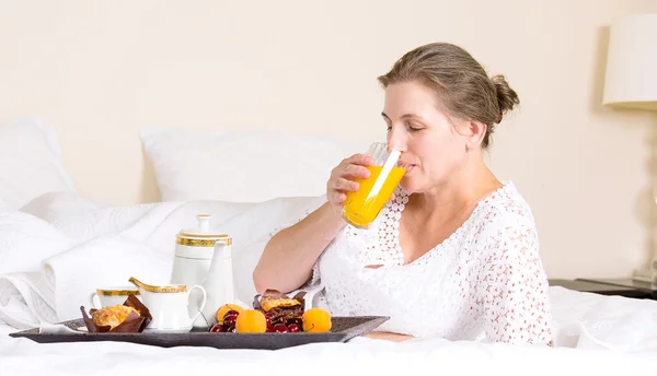 Mulher tomando café da manhã, relaxando na cama do hotel — Fotografia de Stock