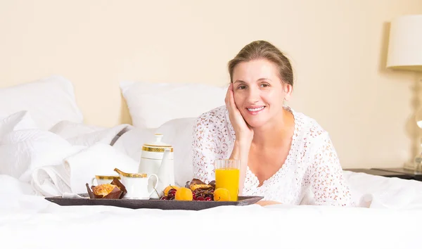 Kvinna med frukost, koppla av i hotel bed — Stockfoto
