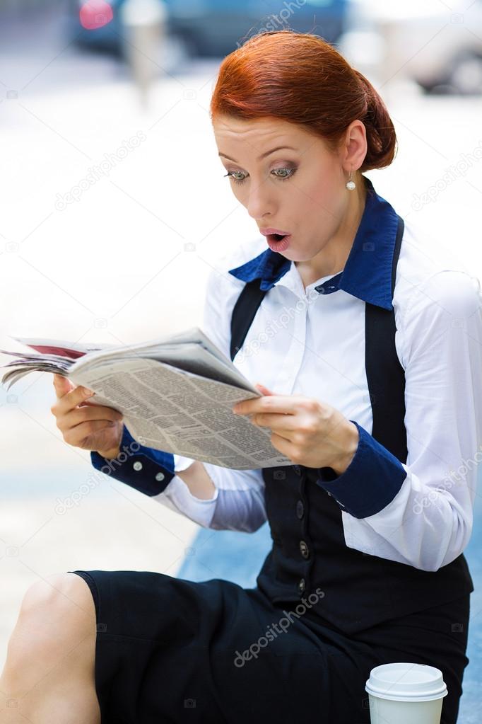 Shocked businesswoman reading newspaper