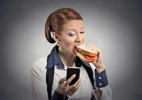 Frau liest Nachricht auf Smartphone und isst Sandwich — Stockfoto