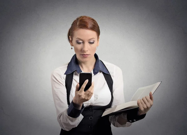 Γυναίκα διαβάζει τις ειδήσεις σχετικά με έξυπνο τηλέφωνο κρατώντας το βιβλίο — Φωτογραφία Αρχείου