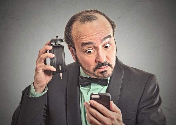 Man with alarm clock looking at his smart phone — Stock Photo, Image