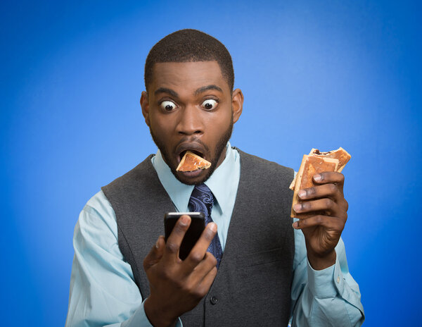 Surprised man using smartphone eating cookie 