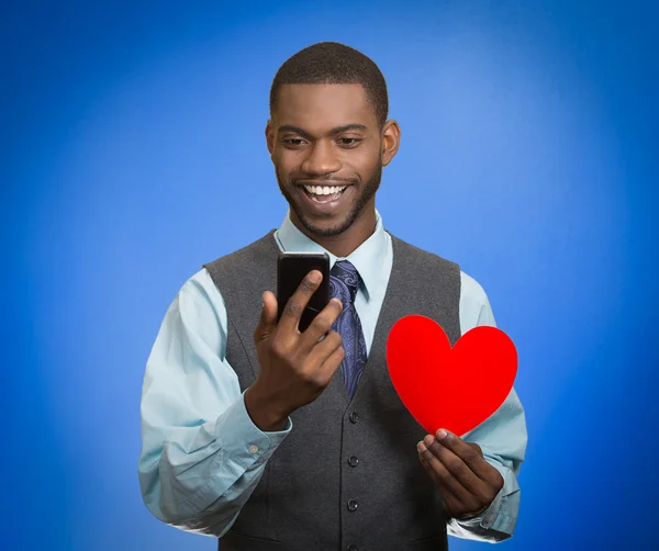 Hombre mirando el teléfono inteligente sosteniendo el corazón rojo — Foto de Stock