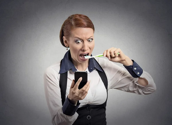 Mujer sorprendida leyendo noticias en teléfono inteligente cepillarse los dientes —  Fotos de Stock