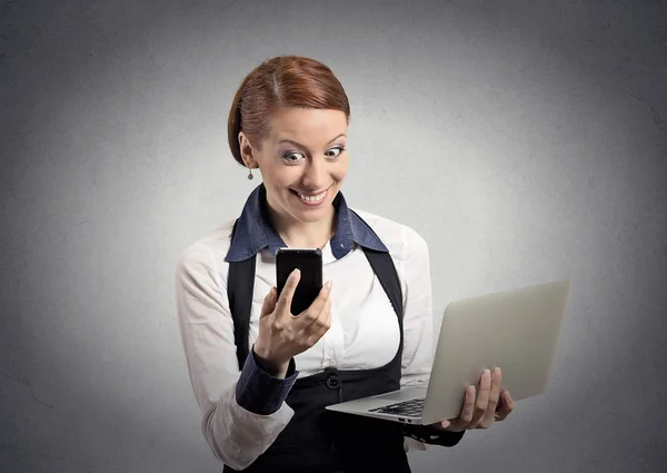 Удивлена женщина читает новости на смартфоне с компьютером — стоковое фото