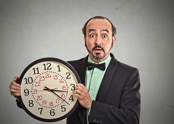 Удивленный бизнесмен в костюме держит настенные часы — стоковое фото