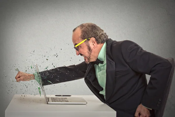 Furious businessman throws a punch into computer — Stock Photo, Image