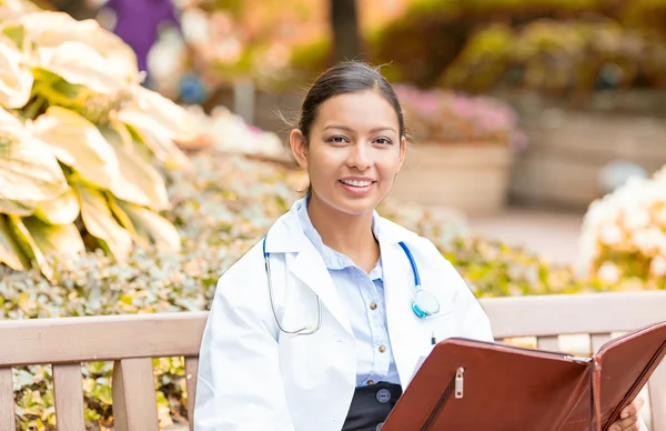 Uśmiechnięty, kobiece kobieta lekarz opieki zdrowotnej zawodowych siedzi na ławce na zewnątrz — Zdjęcie stockowe