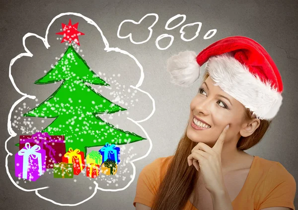 Mujer en rojo santa helper sombrero mirando árbol de Navidad — Foto de Stock