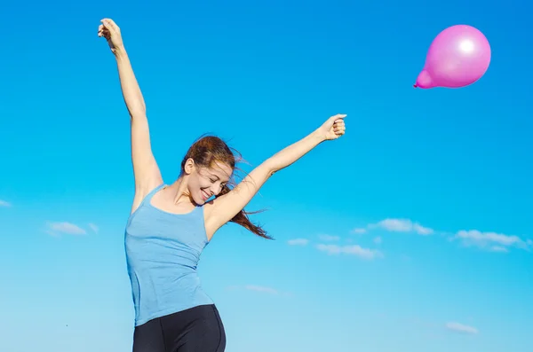 Glücklich lächelnde Frau hebt die Arme und hält rosa Luftballon — Stockfoto