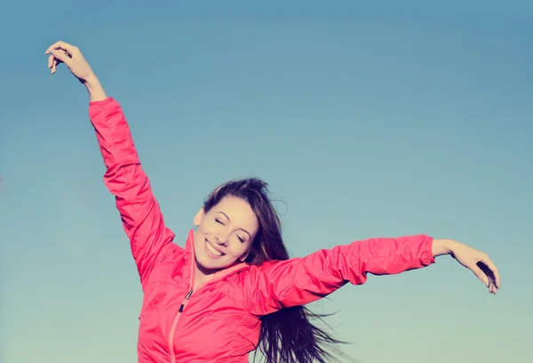 Donna sorridente braccia alzate al cielo blu, celebrando la libertà — Foto Stock