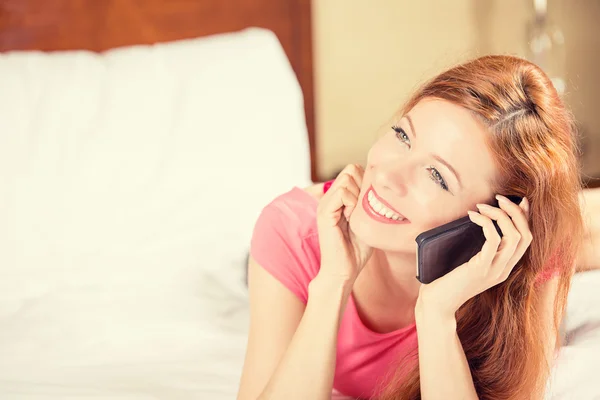 Mulher feliz usando telefone celular deitado na cama — Fotografia de Stock