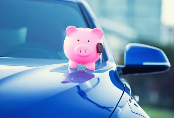 New car with piggy bank, key on hood — Stock Photo, Image
