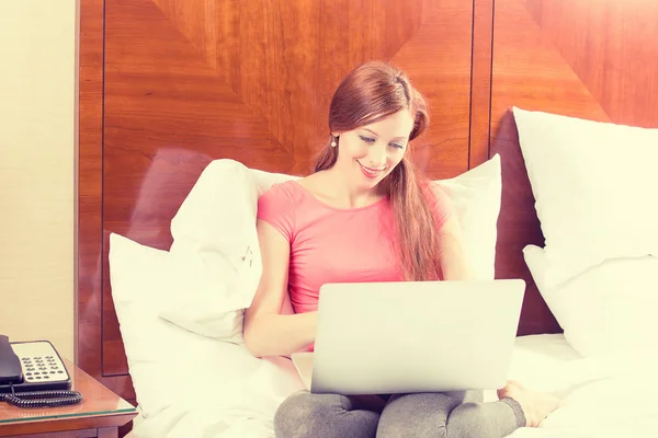 여자 그녀의 노트북 컴퓨터에서 작업을 사용 하 여 편안한 침대에 누워 — 스톡 사진