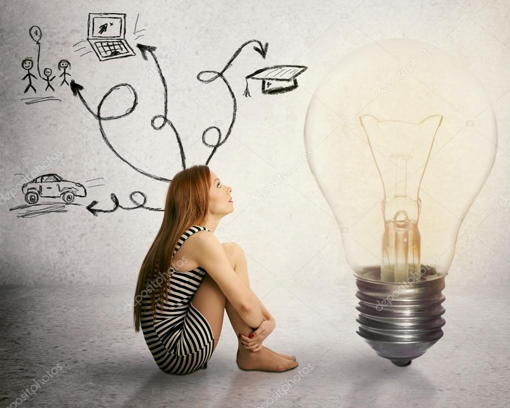 Download - Young woman sitting in front of light bulb thinking has many tho...