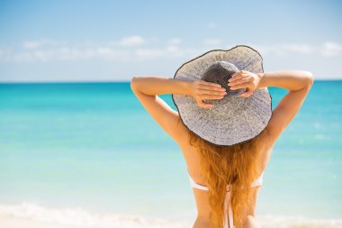 Woman enjoying beach relaxing joyful in summer by tropical blue water clipart