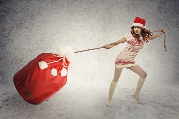 Santa ayudante chica tirando pesado navidad saco — Foto de Stock