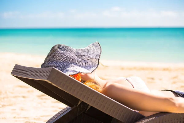 Mujer con sombrero de sol disfrutando de la vista al mar sentada en la silla de una playa — Foto de Stock