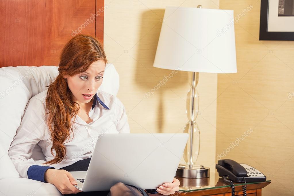 business woman using laptop looking at computer screen blown away in stupor