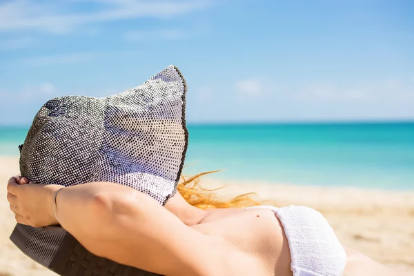 Fiatal nő élvezi a tenger nézet ül egy strand szék szóló kalapról — Stock Fotó