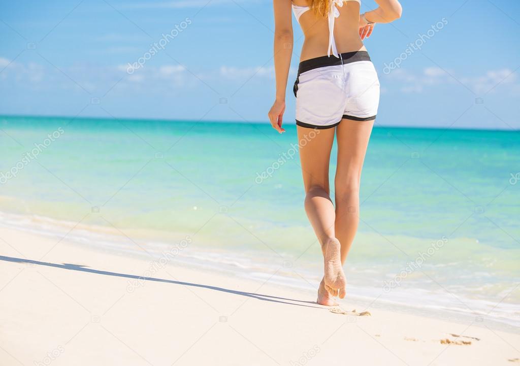 Beach travel. Woman walking on sand beach leaving footprints in the sand