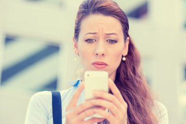 Upset stressed woman holding cellphone disgusted with message she received 