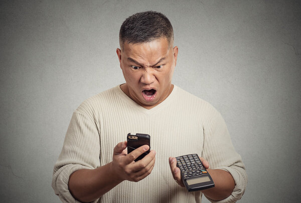 shocked man looking on smartphone calculator disgusted with financial bills