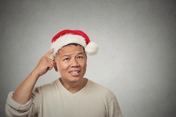 Homem com chapéu vermelho de Papai Noel olhando para cima arranhando cabeça pensando na ideia do presente — Fotografia de Stock