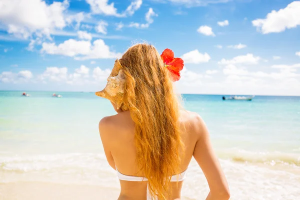 Mulher bonita com concha do mar desfrutando de praia ouvindo o som do oceano — Fotografia de Stock