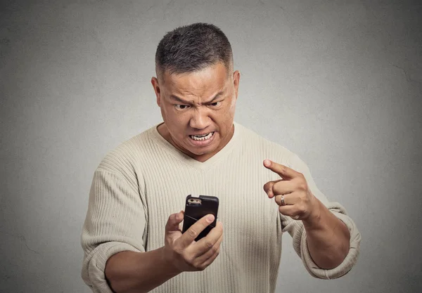 Angry middle aged man while on mobile, pointing at smart phone — Stock Photo, Image