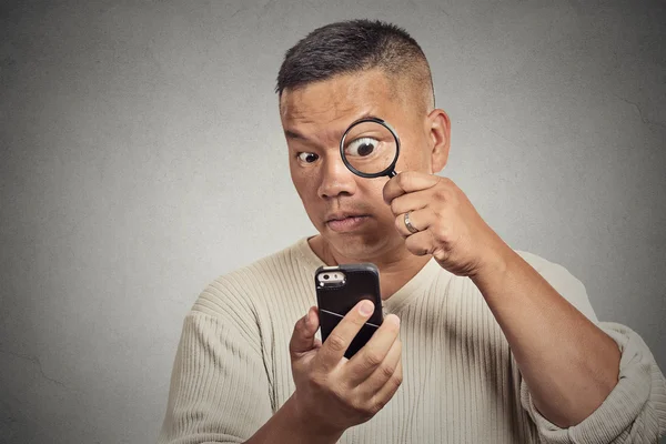 Man looking through magnifying glass on smart phone — Stock Photo, Image